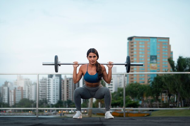 Mulher em forma de tiro completo treinando com barra