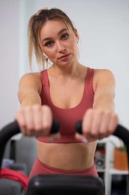 Foto grátis mulher em forma de vista frontal na bicicleta ergométrica