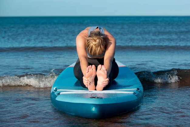 Mulher em foto completa alongando-se no stand up paddle