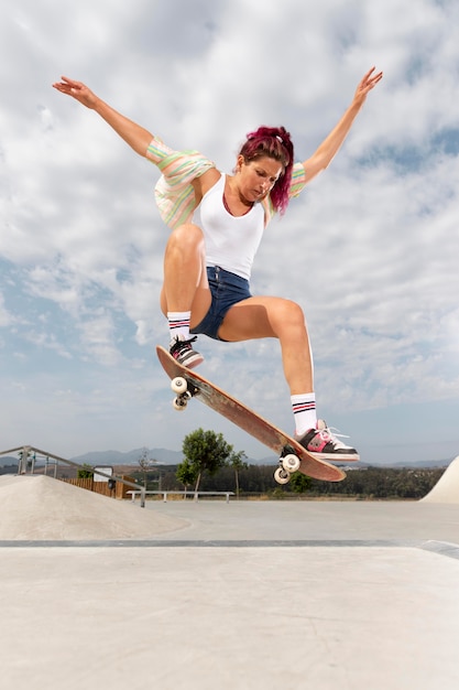 Mulher em foto completa pulando com skate