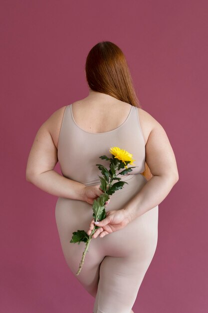 Mulher em foto média segurando a vista de trás da flor