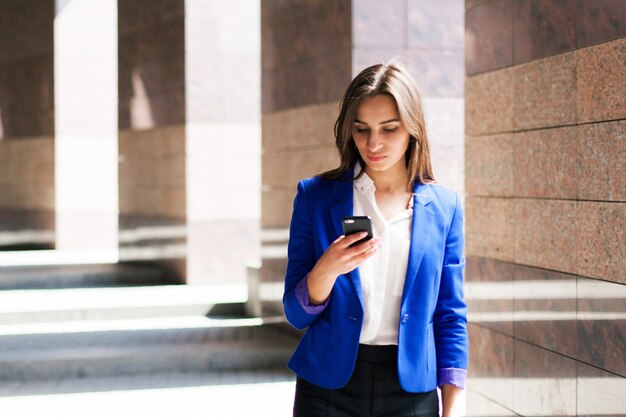 Mulher em jaqueta azul checa seu telefone