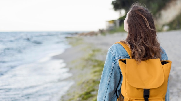 Mulher em meados de tiro com mochila na praia