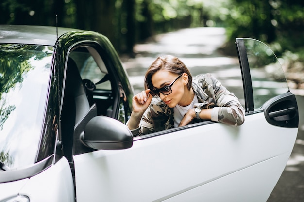 Mulher em pé ao lado do carro no parque