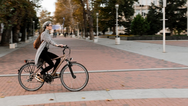 Mulher em pé na bicicleta - tiro longo