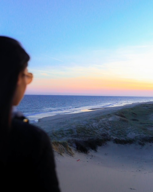 Mulher em pé na praia durante a hora de ouro