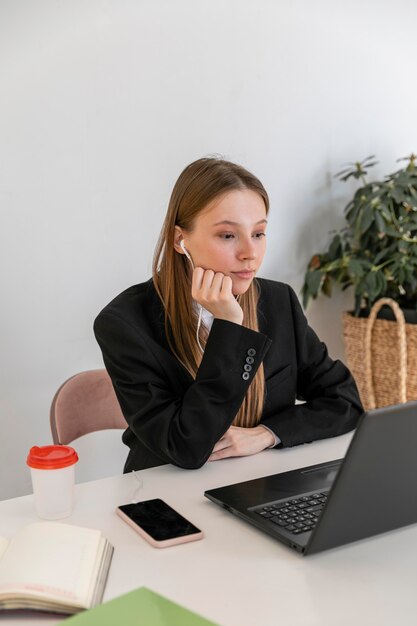 Mulher em plano médio fazendo videochamadas no trabalho