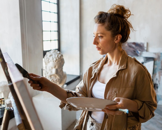 Mulher em plano médio pintando dentro de casa