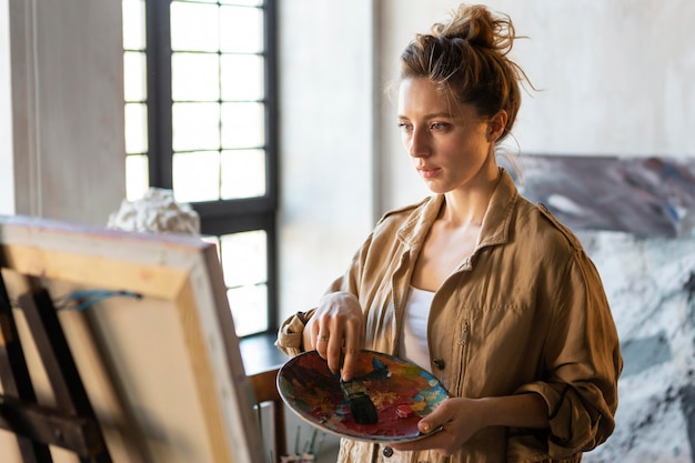 Foto grátis mulher em plano médio segurando uma paleta de pintura