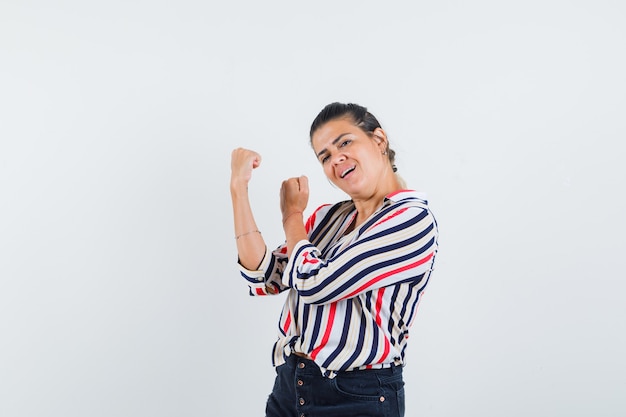 mulher em pose de luta com camisa, saia e parecendo forte