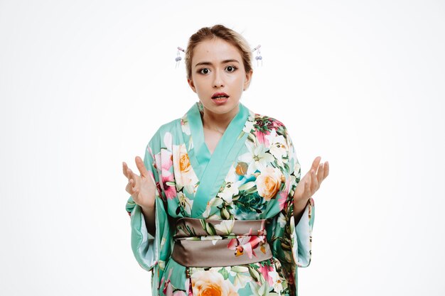 Mulher em quimono japonês tradicional confusa e descontente erguendo os braços em indignação e desagrado em branco