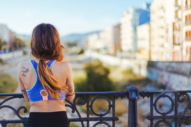 Mulher em roupas esportivas de pé em parapeito