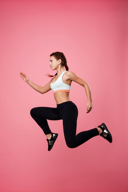 Foto grátis mulher em roupas esportivas finge correr no ar, pulando alto