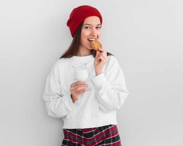 Mulher em tiro médio com chapéu comendo leite e biscoitos