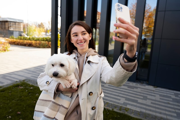 Foto grátis mulher em tiro médio tirando selfie com cachorro