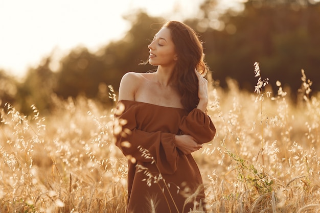 Mulher em um campo de verão. Morena com um suéter marrom.