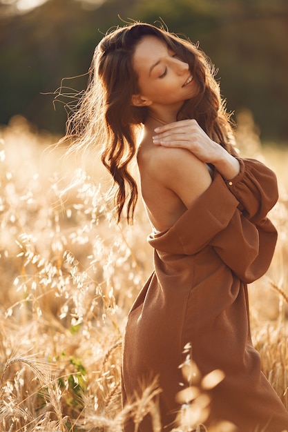 Mulher em um campo de verão. Morena com um suéter marrom.