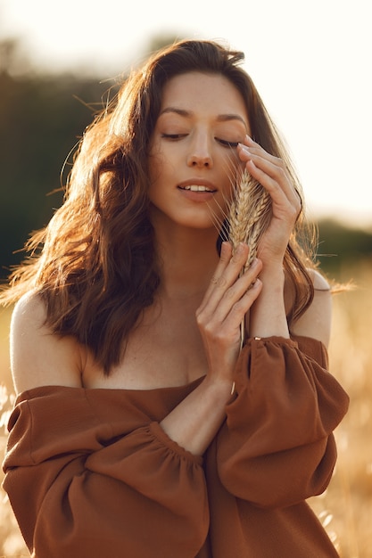 Mulher em um campo de verão. Morena com um suéter marrom.