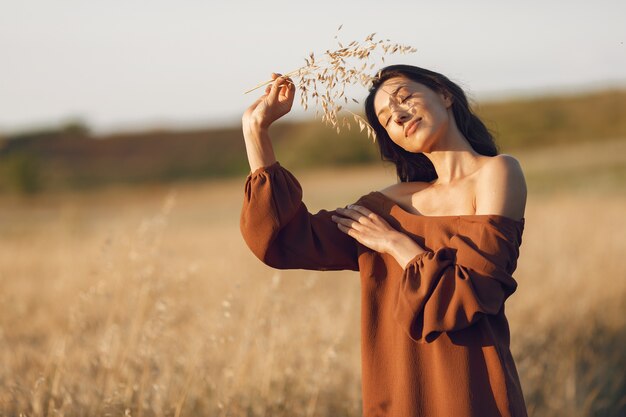 Mulher em um campo de verão. Morena com um suéter marrom.