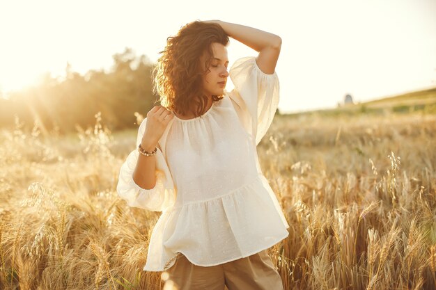 Mulher em um campo de verão. Morena em uma camisa branca.