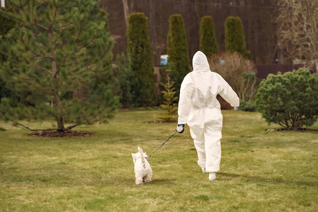 Mulher em um traje de proteção andando com um cachorro