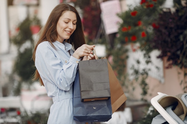 Mulher em um vestido azul com sacola de compras em uma cidade