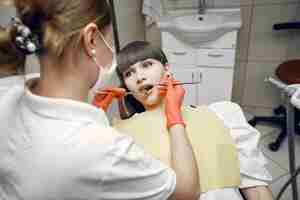 Foto grátis mulher em uma cadeira de dentista. a menina é examinada por um dentista. a beleza trata os dentes