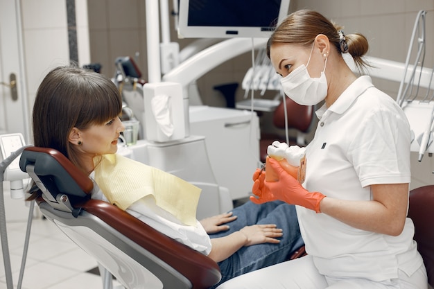 Mulher em uma cadeira odontológica. O dentista ensina os cuidados adequados. A beleza trata os dentes