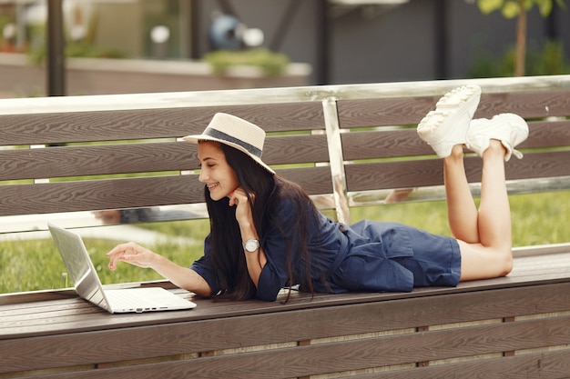 Mulher em uma cidade de primavera. senhora com um laptop. menina sentada em um banco.