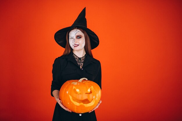 Mulher em uma fantasia de halloween com uma abóbora