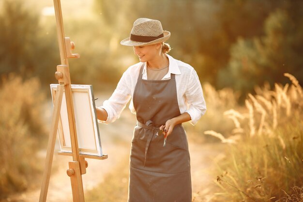 Mulher em uma pintura de avental em um campo