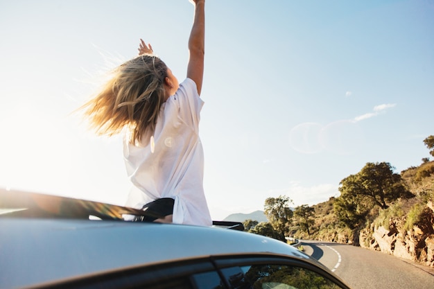 Foto grátis mulher em viagem de carro acenando pela janela sorrindo.