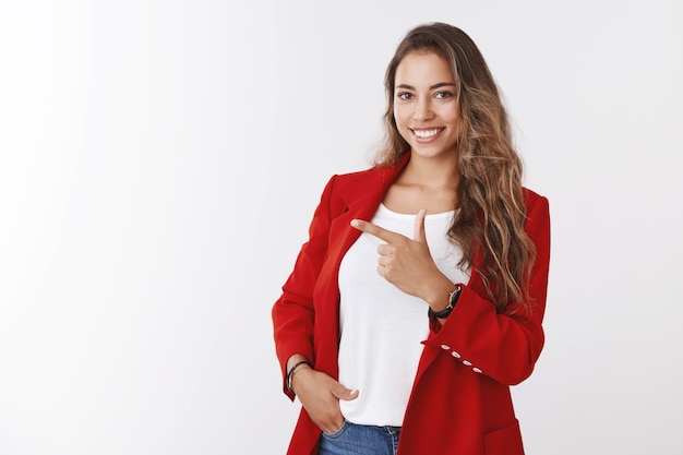 Foto grátis mulher empreendedora assertiva e bonita em pé pose confiante, bolso da mão apontando o dedo indicador de lado, mostrando o espaço da cópia, confiante e habilidosa empresária oferecendo uma promoção interessante