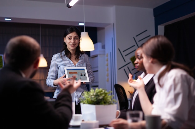 Mulher empreendedora workaholic sobrecarregada exibindo gráficos de marketing usando um tablet