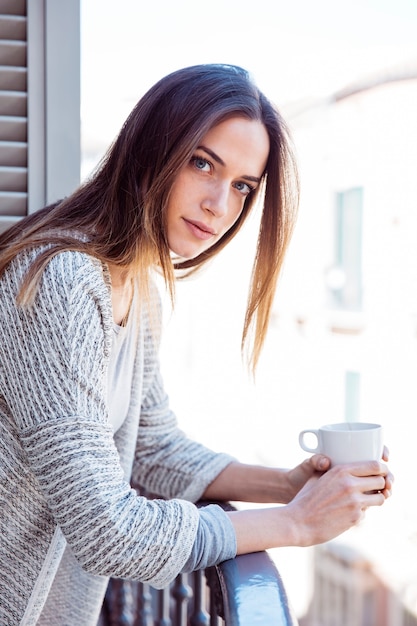 Mulher encantadora com caneca na varanda