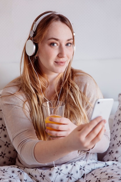 Foto grátis mulher encantadora com suco e smartphone