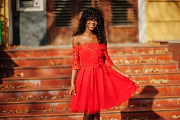 Mulher encaracolada afro-francesa elegante posou no dia do outono em vestido vermelho Modelo feminino africano negro
