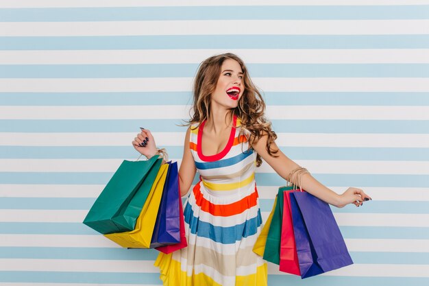 Mulher encaracolada satisfeita, aproveitando as vendas. retrato de uma linda garota dançando depois das compras.