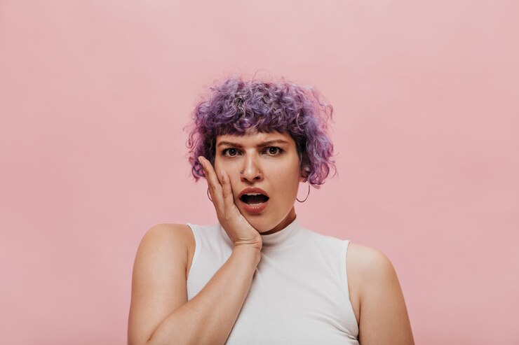 Foto grátis mulher encaracolada surpresa em top branco posando. mulher de cabelo curto com brincos redondos na cor rosa.