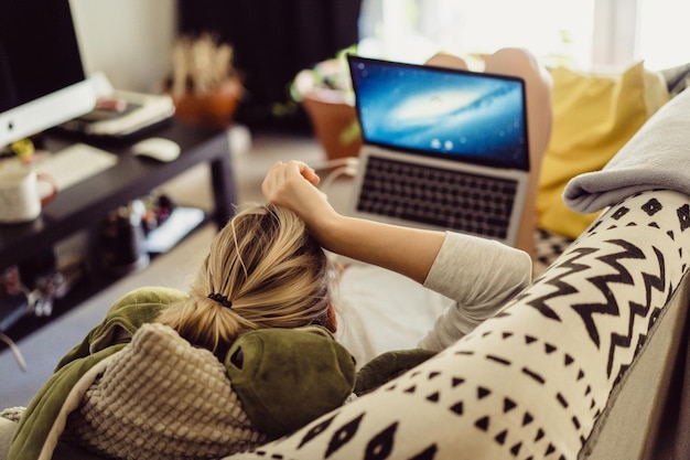 mulher encontra-se em um sofá com um laptop. Lazer no isolamento. Trabalhando em um laptop em casa.