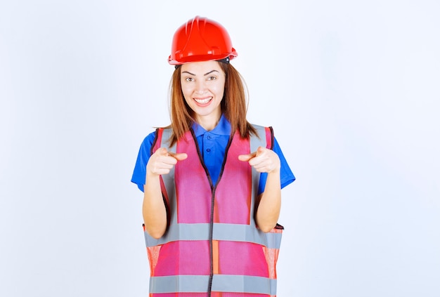 Foto grátis mulher engenheira de uniforme e capacete vermelho observando a pessoa à frente.