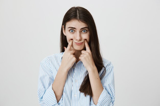 Mulher engraçada e boba sorrindo com os dedos nas bochechas