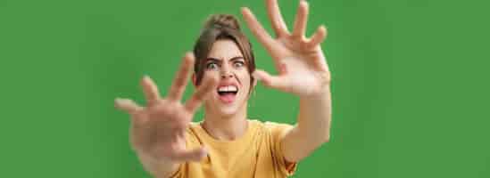 Foto grátis mulher engraçada e emotiva fazendo careta puxando as mãos para a frente para atacar ou pegar algo carrancudo aberto