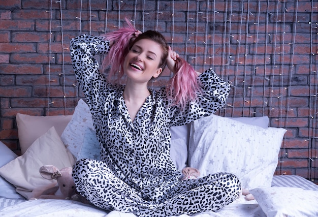 Foto grátis mulher engraçada senta-se na cama de pijama de leopardo e sorrisos