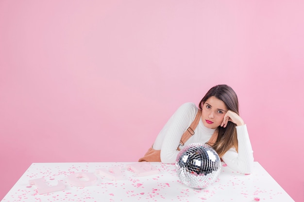 Foto grátis mulher entediada sentado à mesa com bola de discoteca