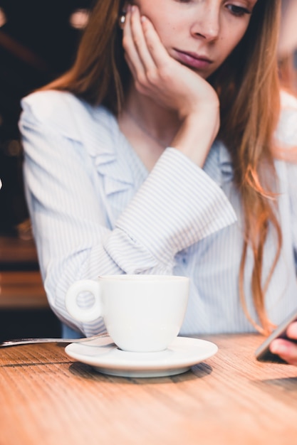 Mulher entediada usando smartphone no café