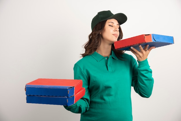 Mulher entregadora cheirando a caixa de pizza.