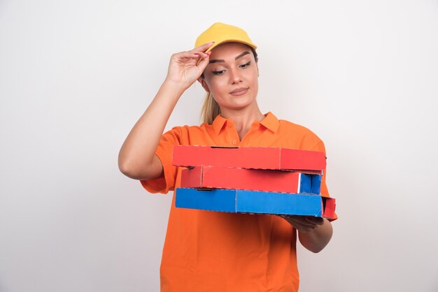 Mulher entregadora de pizza segurando caixas de pizza em fundo branco.