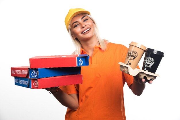 Mulher entregadora de pizza segurando pizza e cafés em fundo branco. Foto de alta qualidade