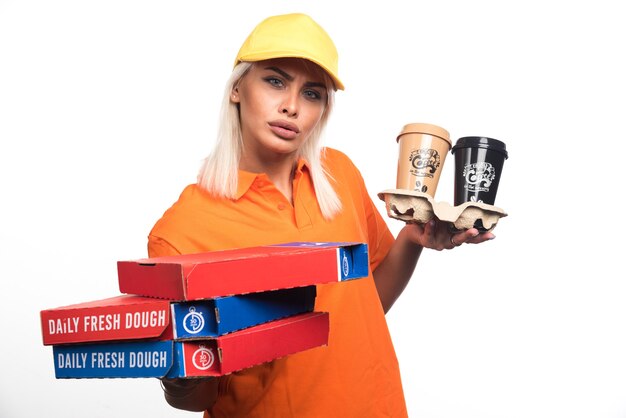 Mulher entregadora de pizza segurando pizza e cafés em fundo branco. Foto de alta qualidade